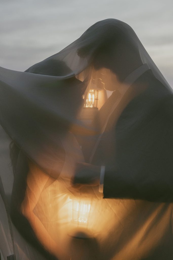 couple under veil at ruby beach elopement with lanterns
